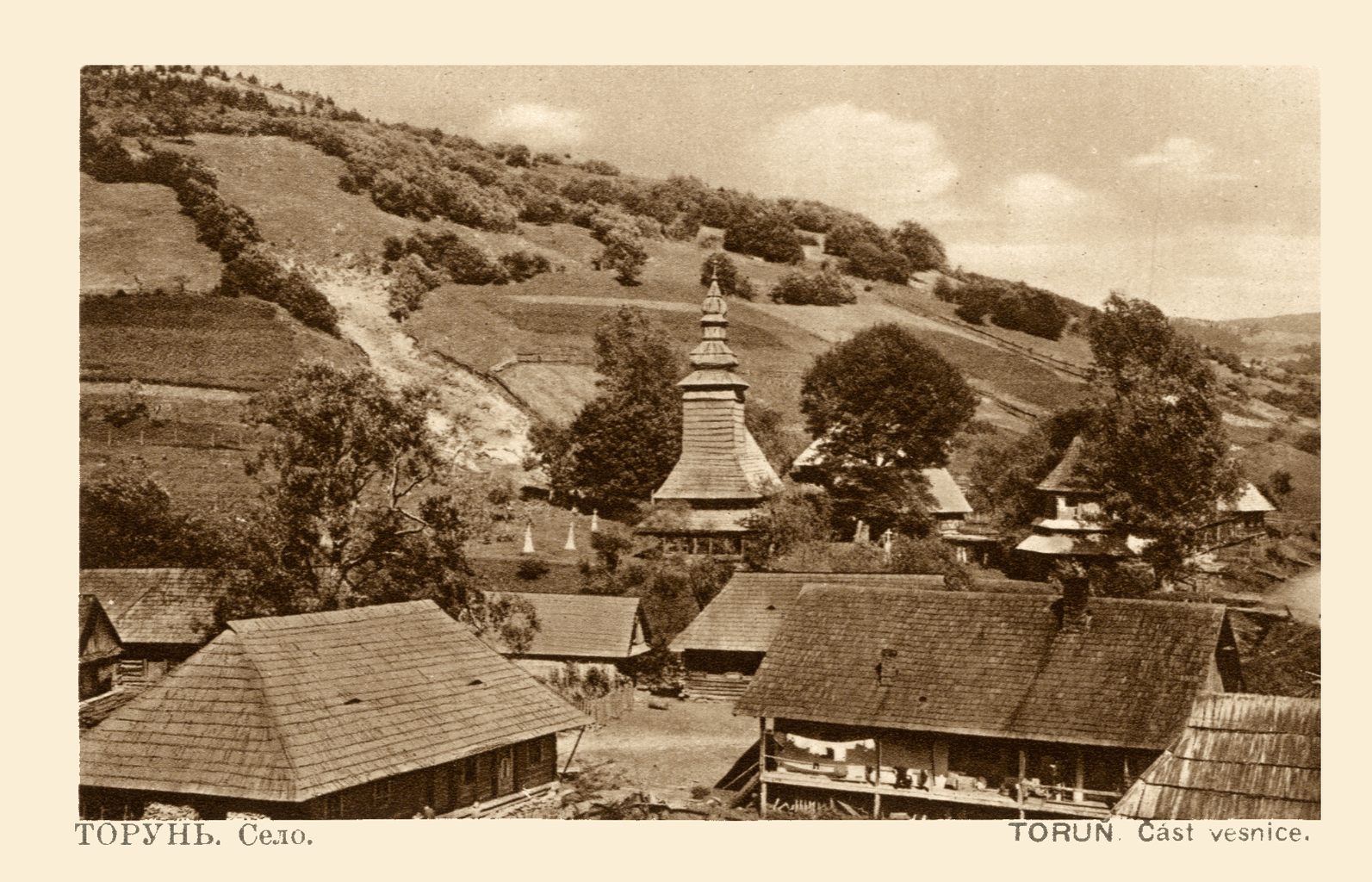 Sepia postcard from the 1920s: the village of Torun in Zakarpattia — shingled roofs, a wooden church tower, field-striped hills